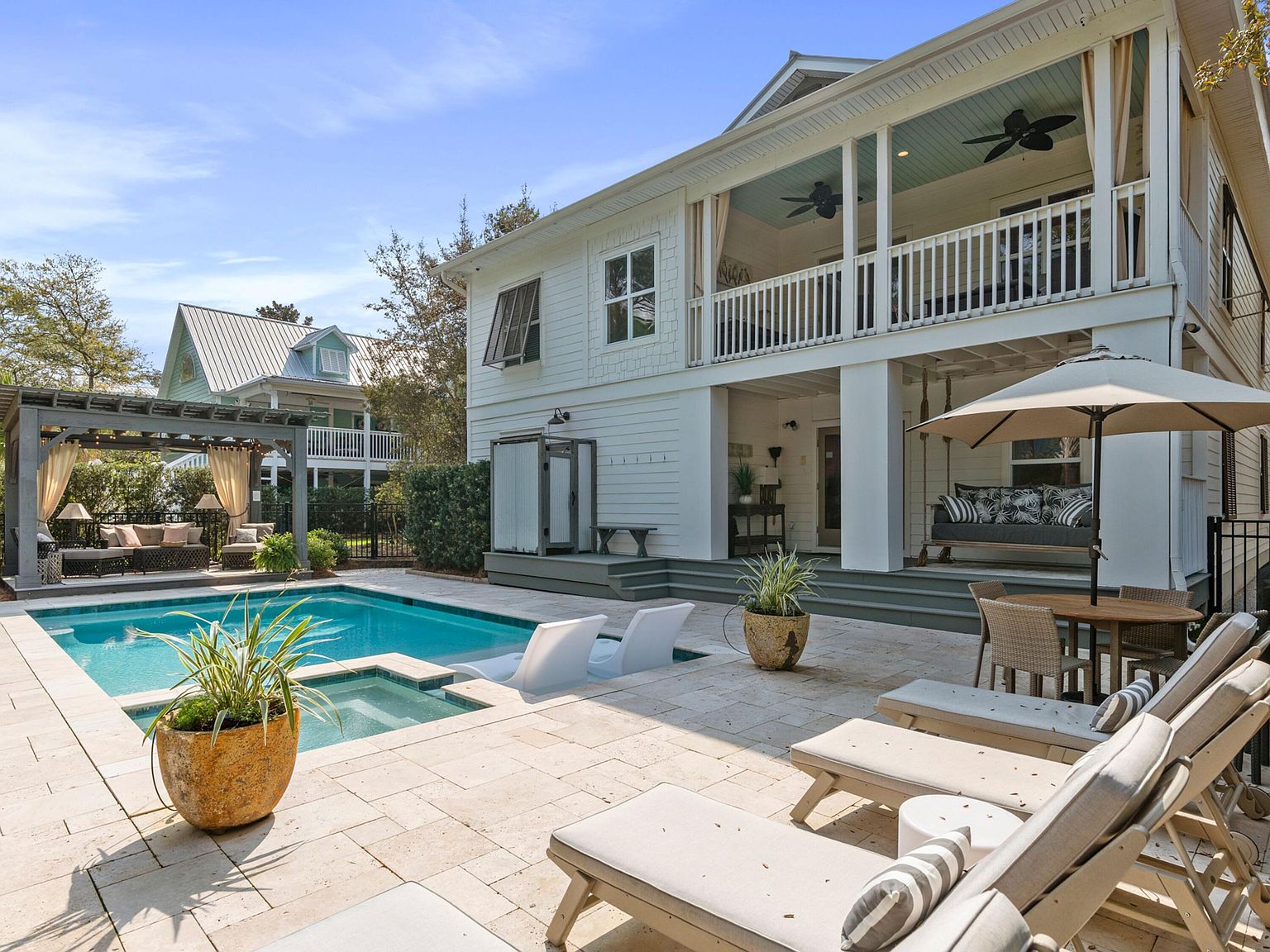 Pool deck and back of the canal front residence at 499 Lakeview Drive, Santa Rosa Beach, with covered porches and palms